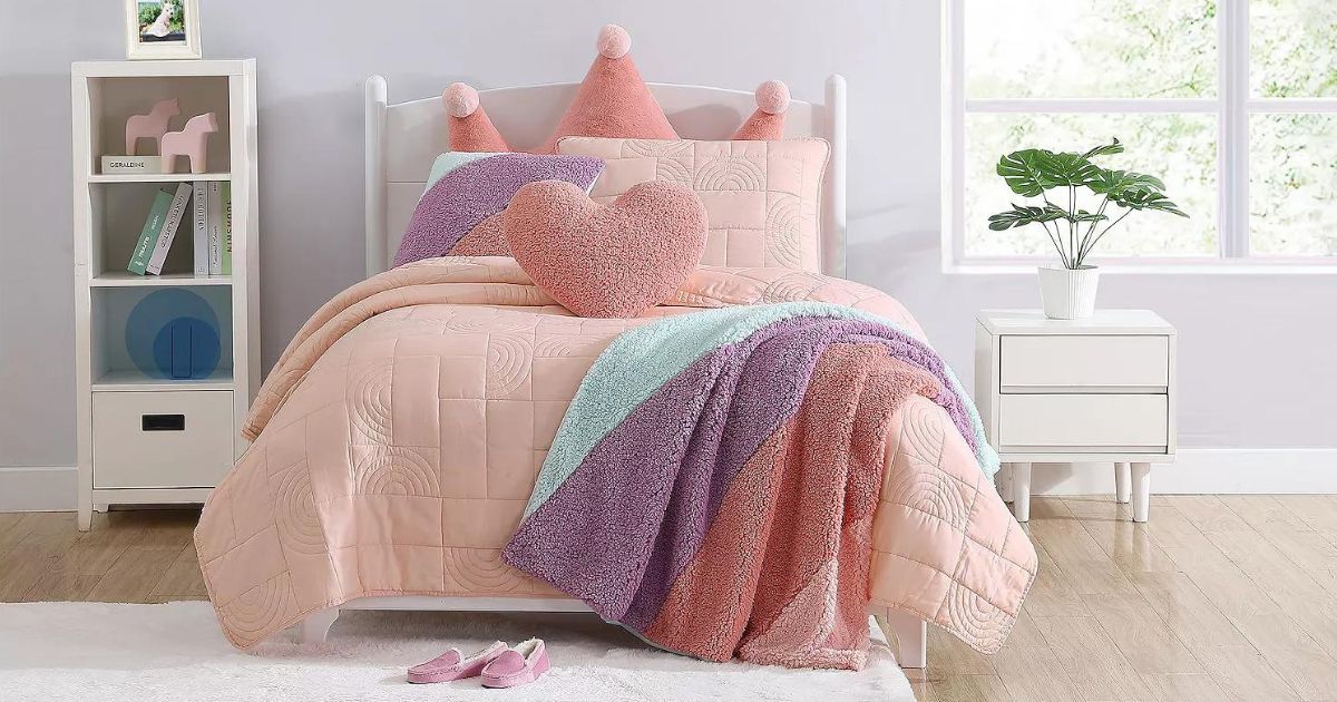 a child's room with a pink comforter with a throw blanket and colorful pillows