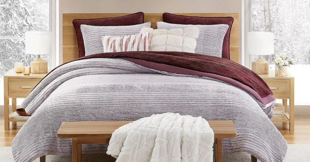 a bed with a gray and maroon bed spread