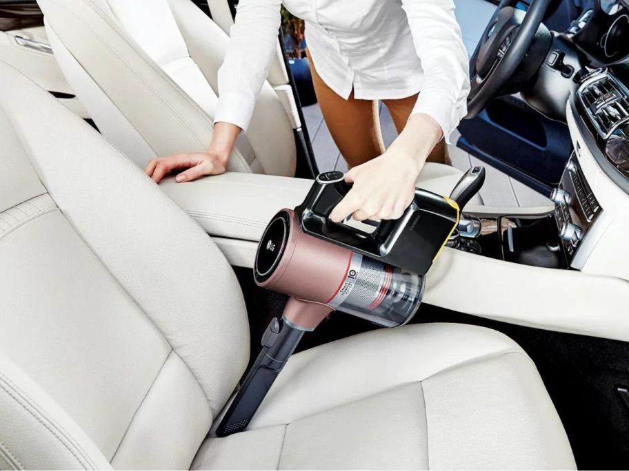 A woman cleaning her car with a LG Cord Zero A9 Cordless Stick Vacuum