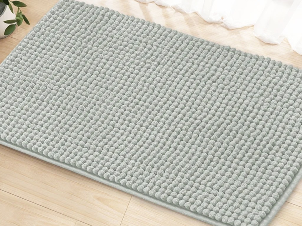 light grey bath rug on wood floor