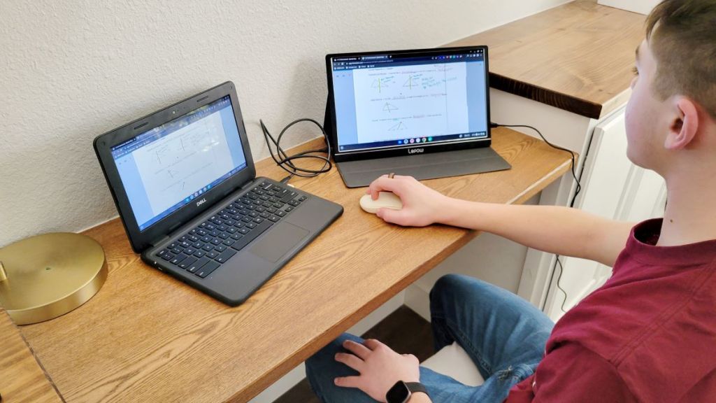 Boy working on a laptop with a portable monitor next to it