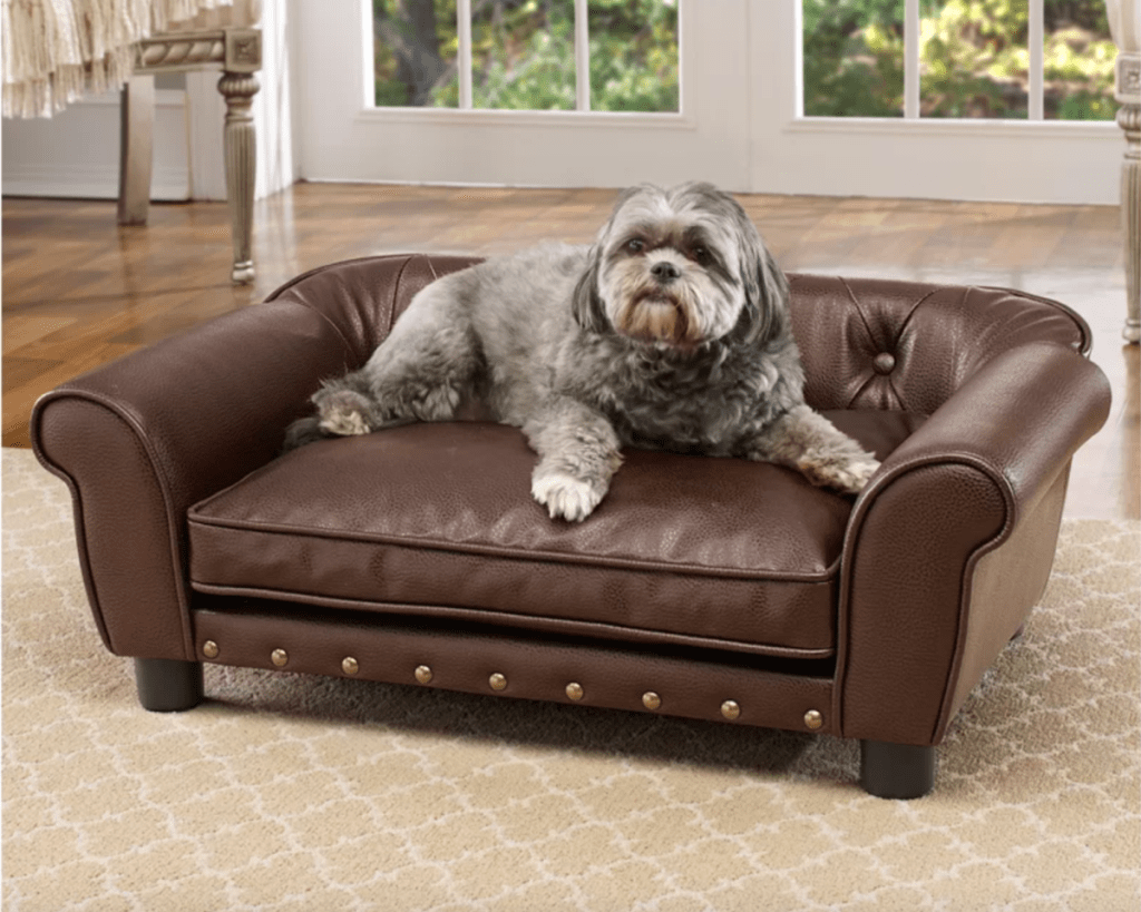 a dog lounging on the faux leather longworth dog couch bed from wayfair