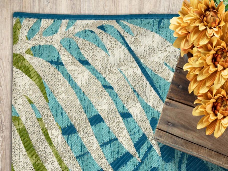 A Mainstays rug with palm fronds on it near a table