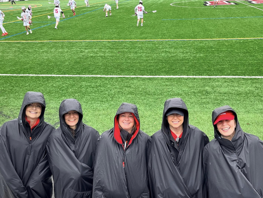row of women in waterproof blanket blanket jackets at lacrosse field