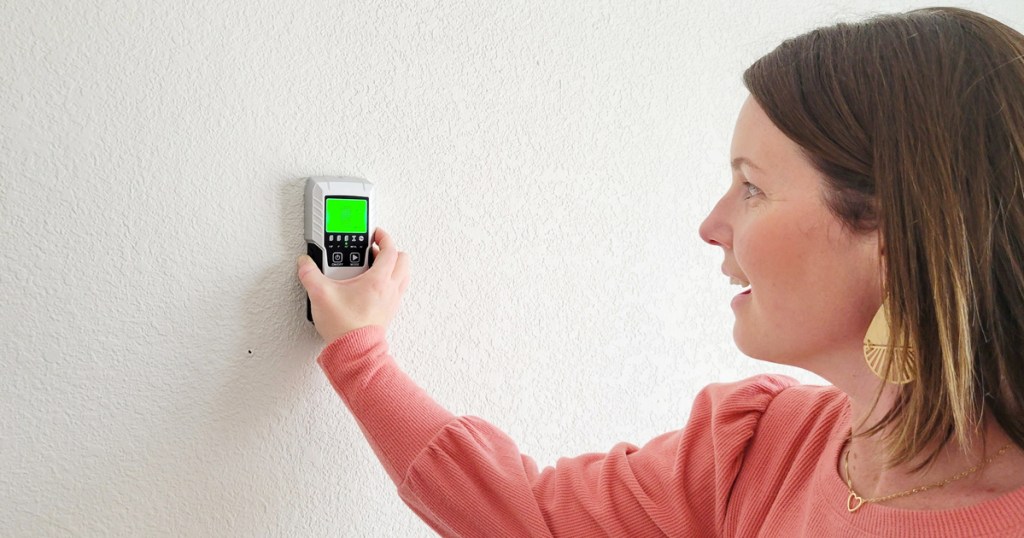 woman using stud finder on a wall