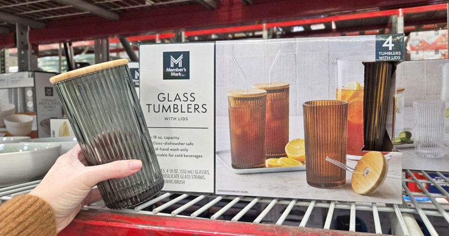 hand holding a black glass tumbler next to a box of tumblers on store shelf