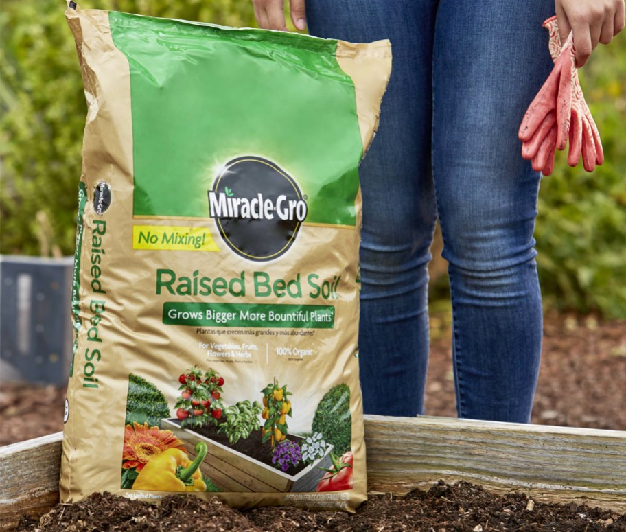 woman standing next to a bag of Miracle-Gro Raised Bed Soil