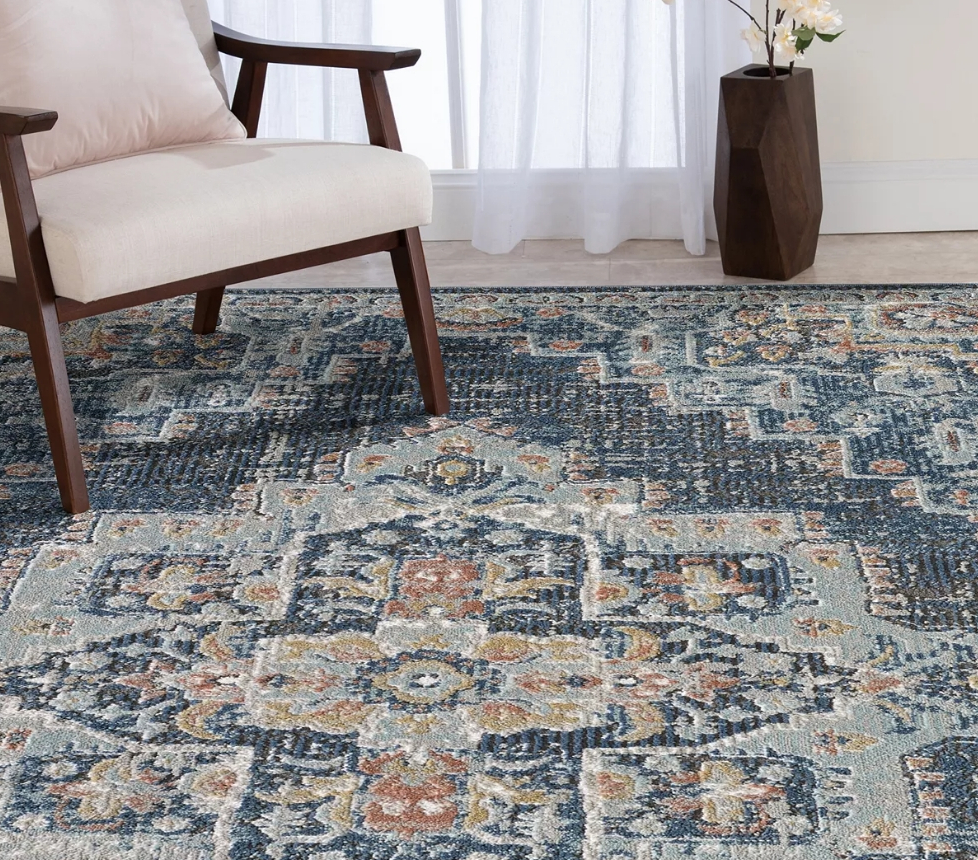 White chair sitting on a rug that has a distressed blue medallion design on it