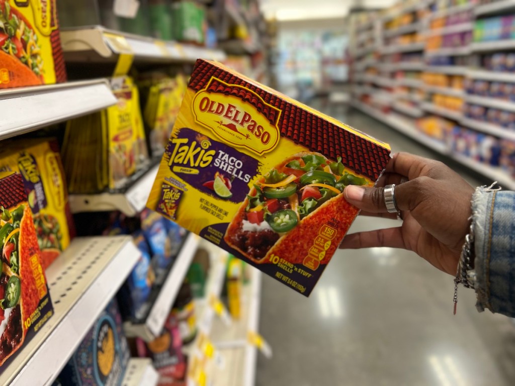 Hand holding a box of Old El Paso taco shells by a shelf at a store