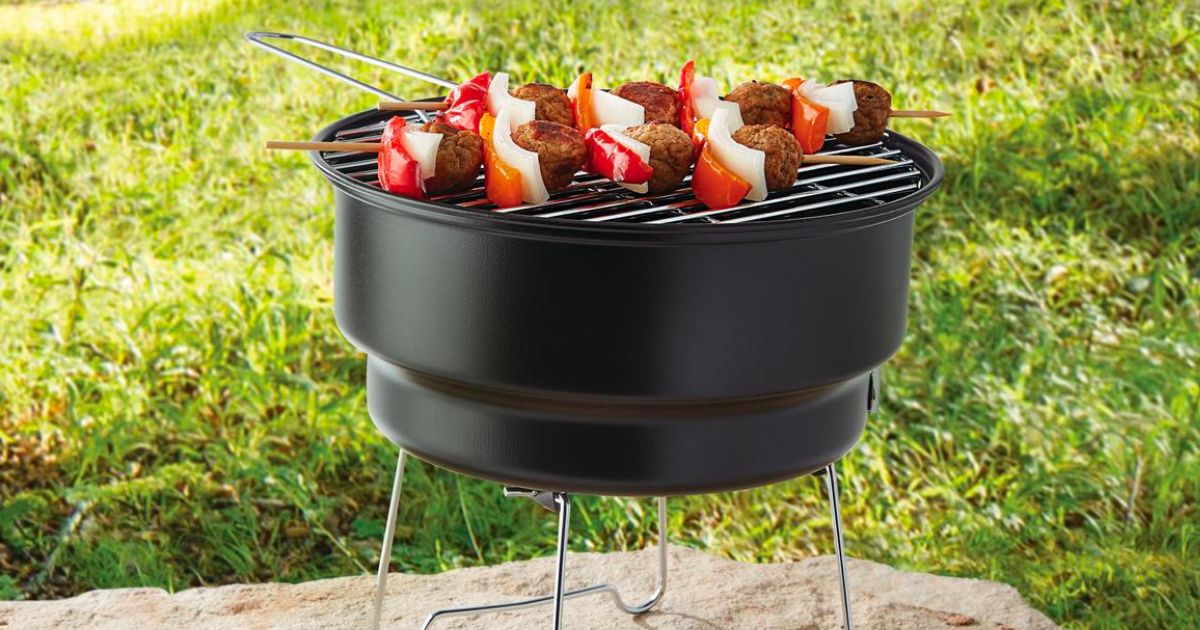 Ozark Trail 10 Portable Charcoal Grill sitting outside with skewers grilling on it