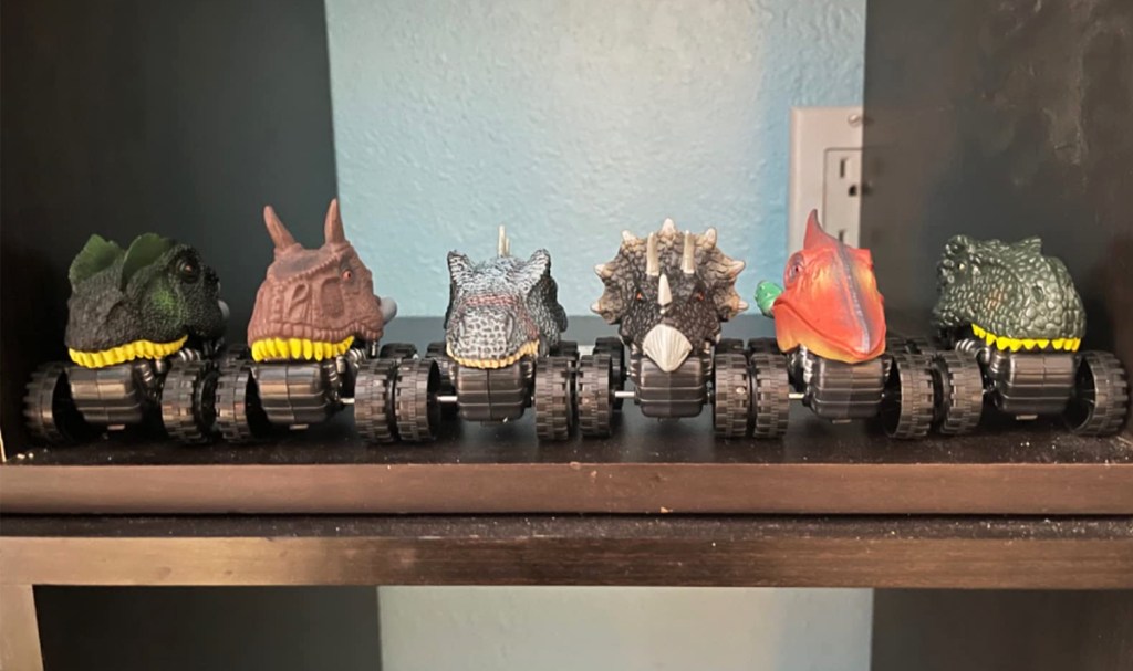 6 mini dinosaur toys on a wood shelf