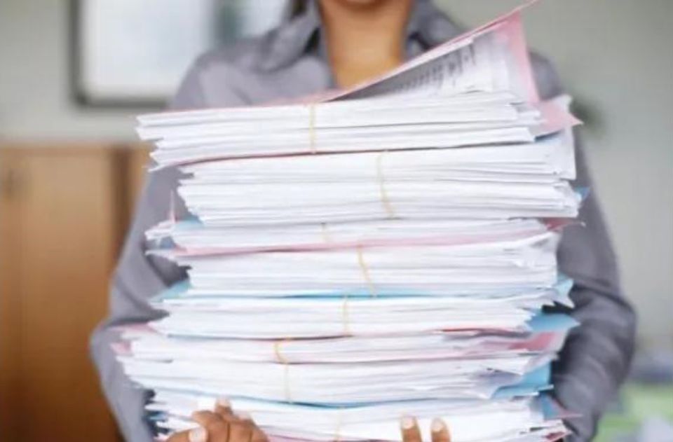 Woman carrying a large stack of paper