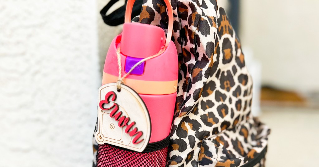 wood name tag hanging on water bottle in a leopard print backpack