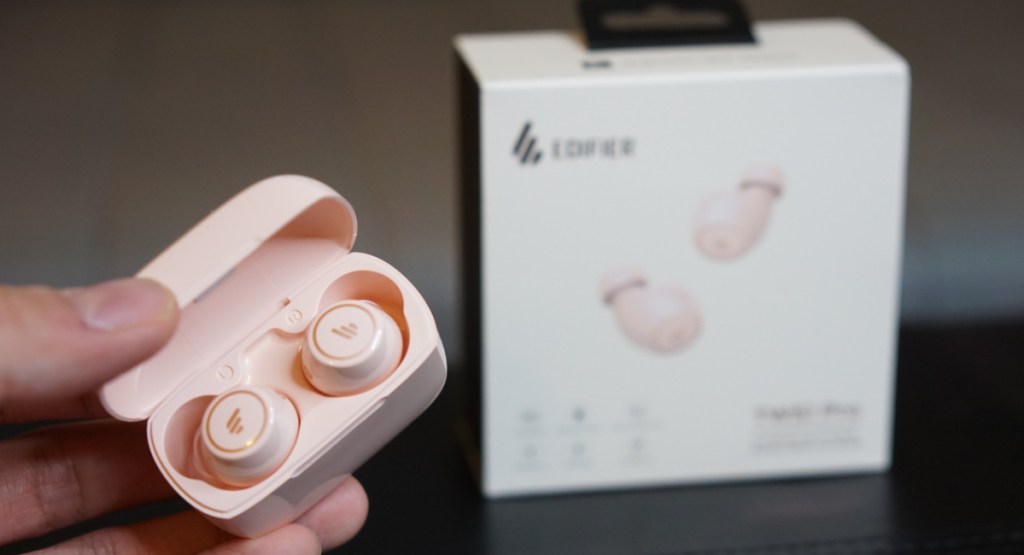 Pink wireless earbud in case next to the box