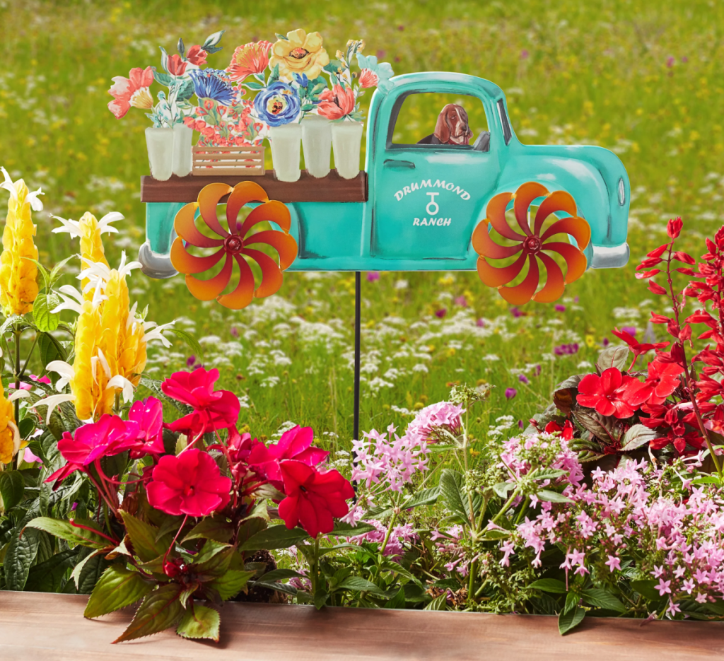 Metal yard pickup truck decoration from the Pioneer Woman Patio Collection being displayed near flowers