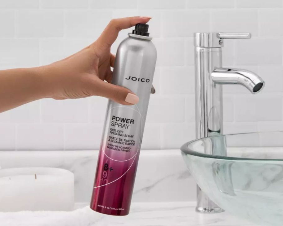 a womans hand holding a can of joico finishing spray