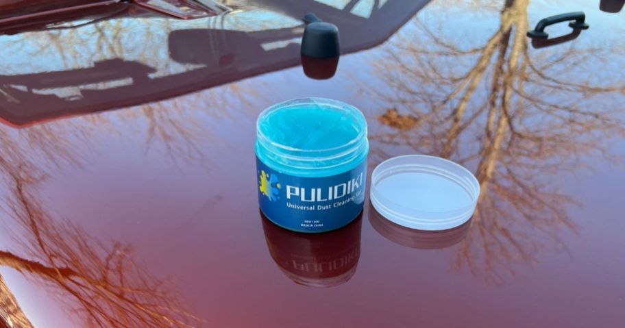 An open canister of Pulidiki cleaning gel on the hood of a car