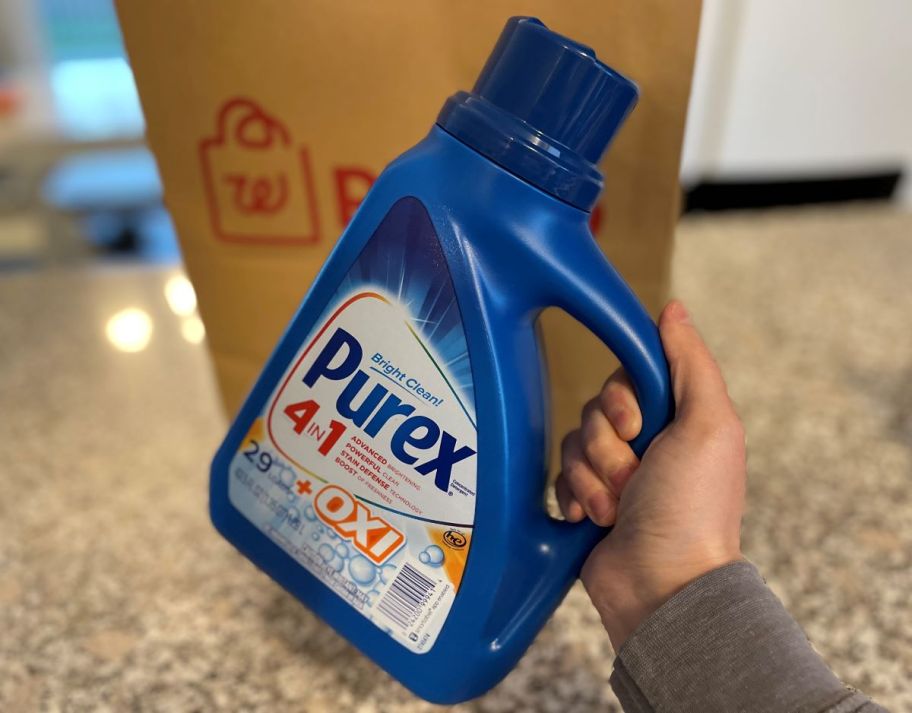 Hand holding a bottle of Purex Laundry Detergent