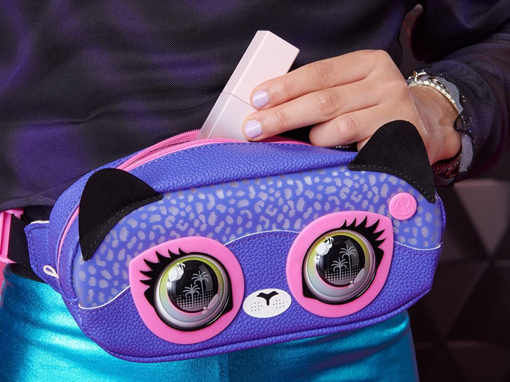 Mädchen steckt Lipgloss in lila Handtasche, Haustier-Gürteltasche