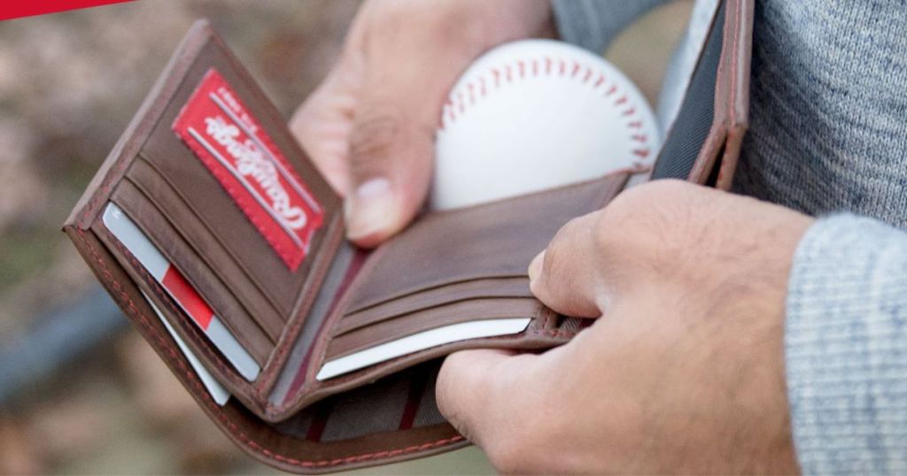 Hands holding a leather wallet and a baseball