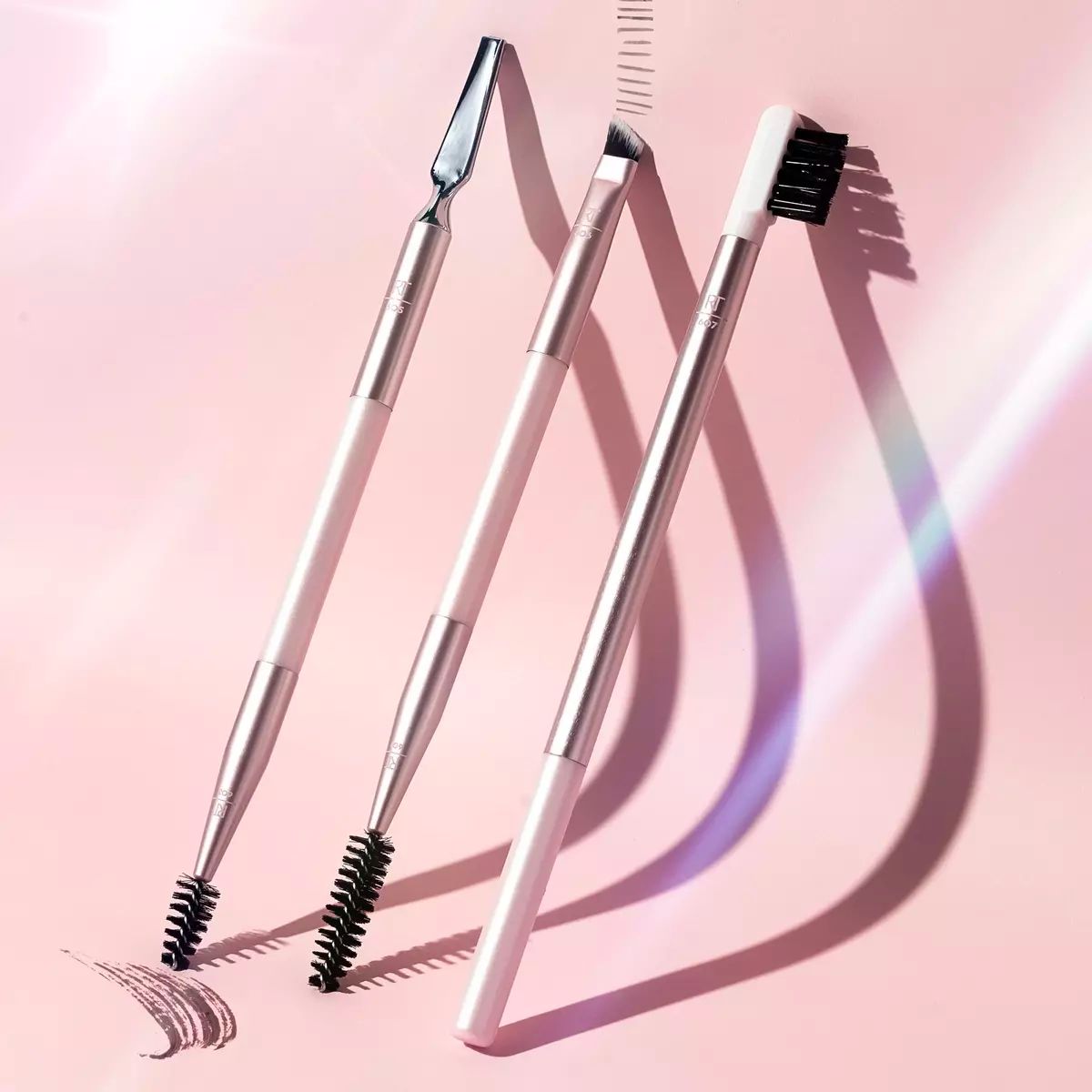 Real Techniques Brow Styling Makeup Brush and Tool Set displayed on a pink background
