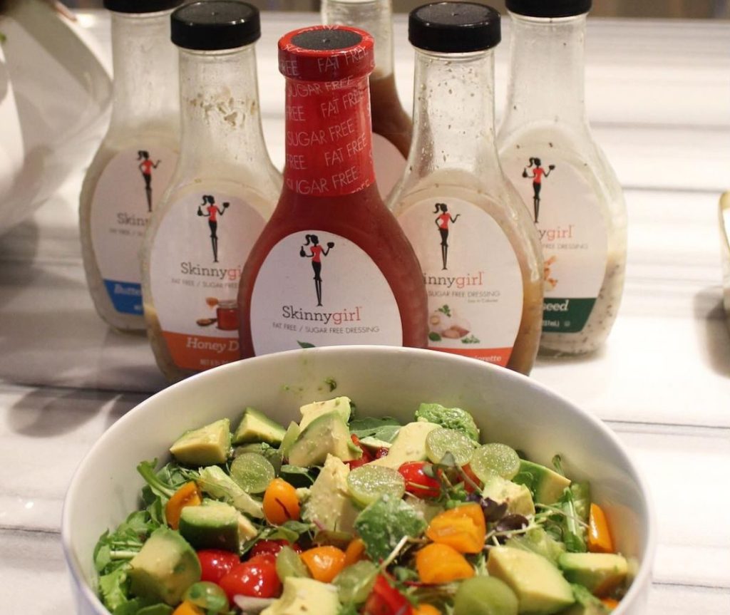 SKinnygirl Dressings lined up behind a big bowl of salad