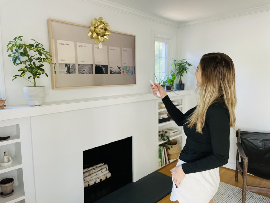 Woman admiring her Samsung Frame TV which hangs above her fireplace