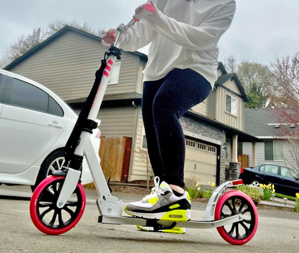 woman standing on a white and pink scooter