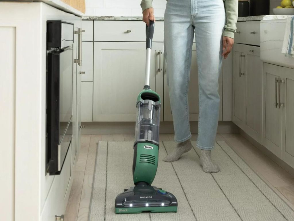 Frau, die einen Küchenboden saugt