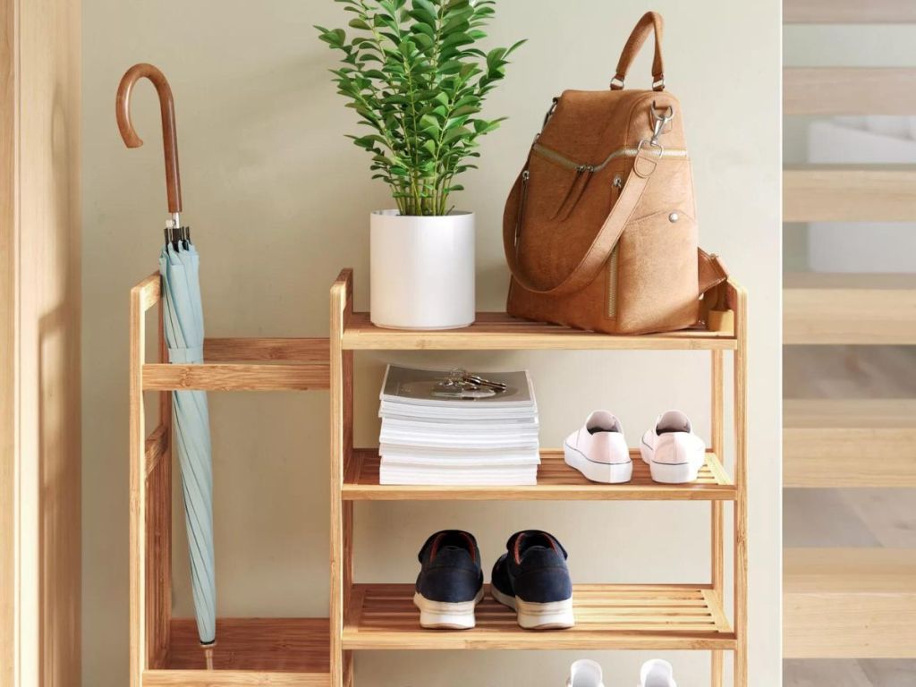 Bamboo shoe rack with an umbrella on the side and a plant and backpack on the top