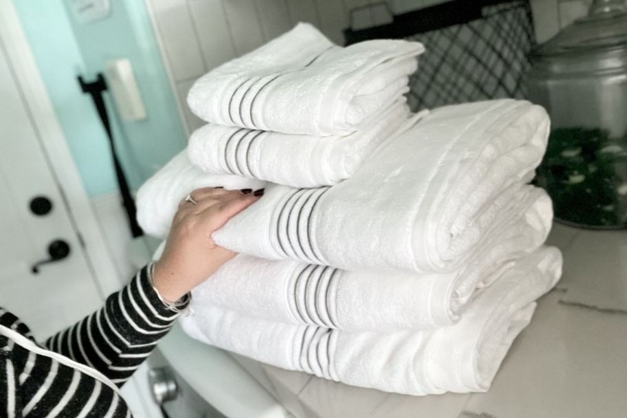 hand touching stack of white Simply vera wang towels
