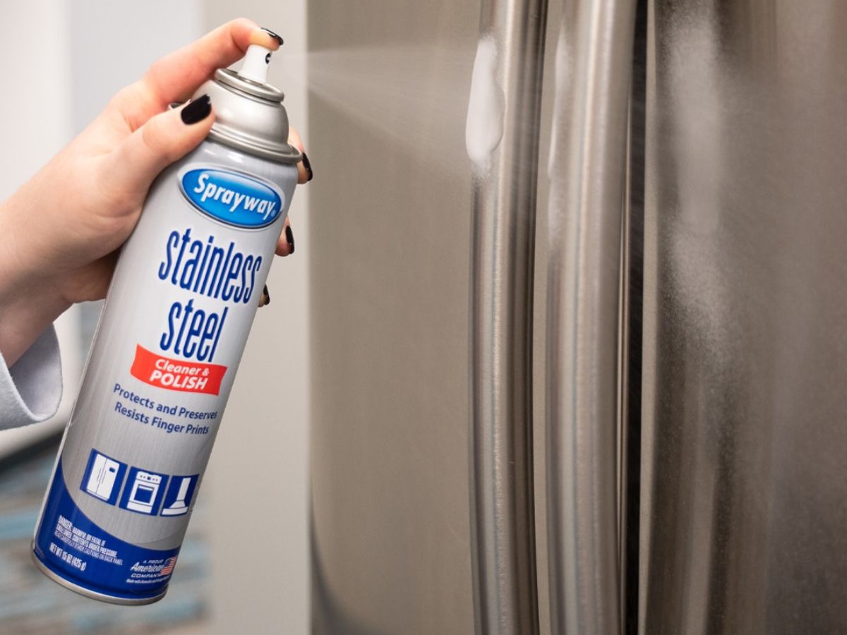 Hand spraying Sprayway Stainless cleaner on a fridge door handle