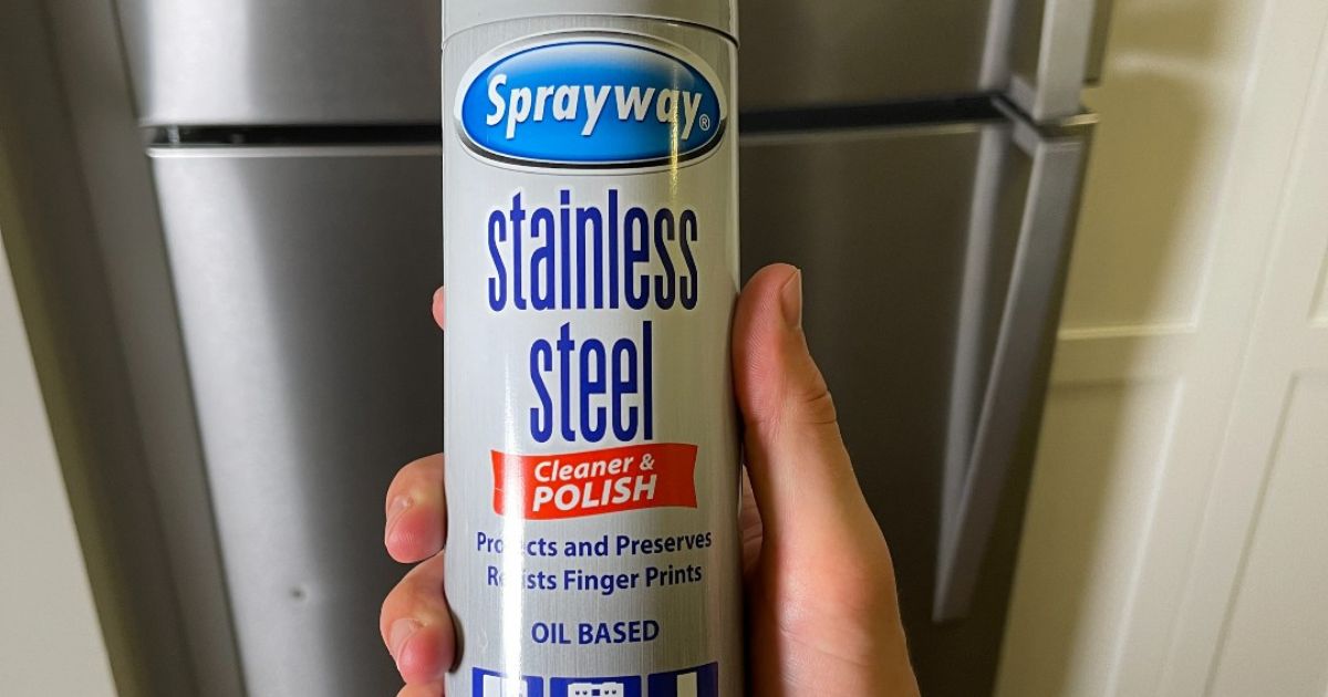 Hand holding a can of Sprayway Stainless Cleaner in front of a Stainless Steel fridge