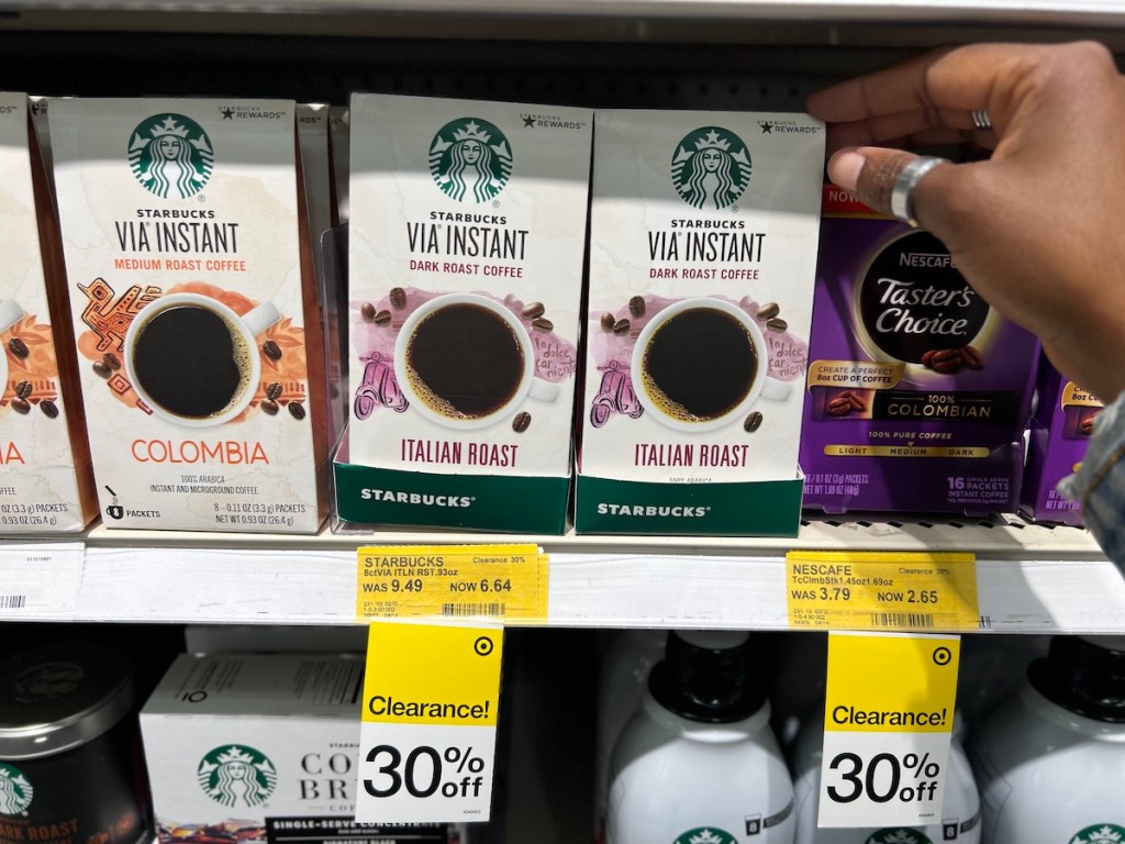 Hand grabbing a box of Starbucks VIA Box of Instant Coffee Dark Roast Packets off the shelf at Target