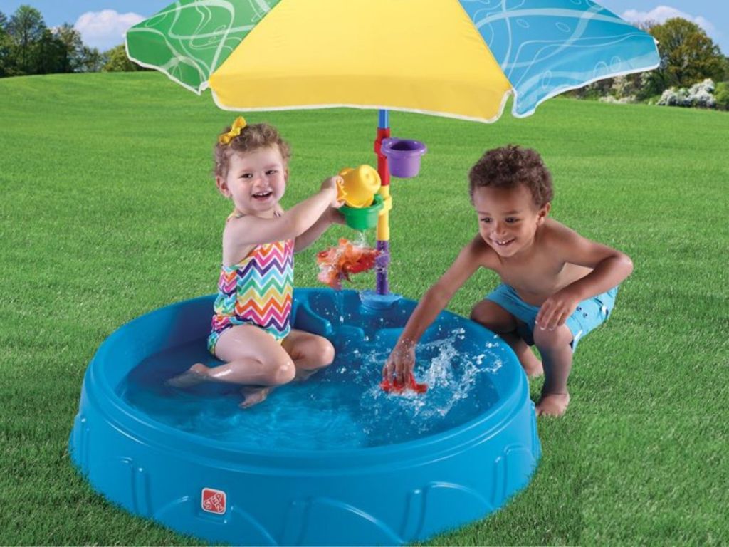 Kids playing in a small pool with an umbrella over it