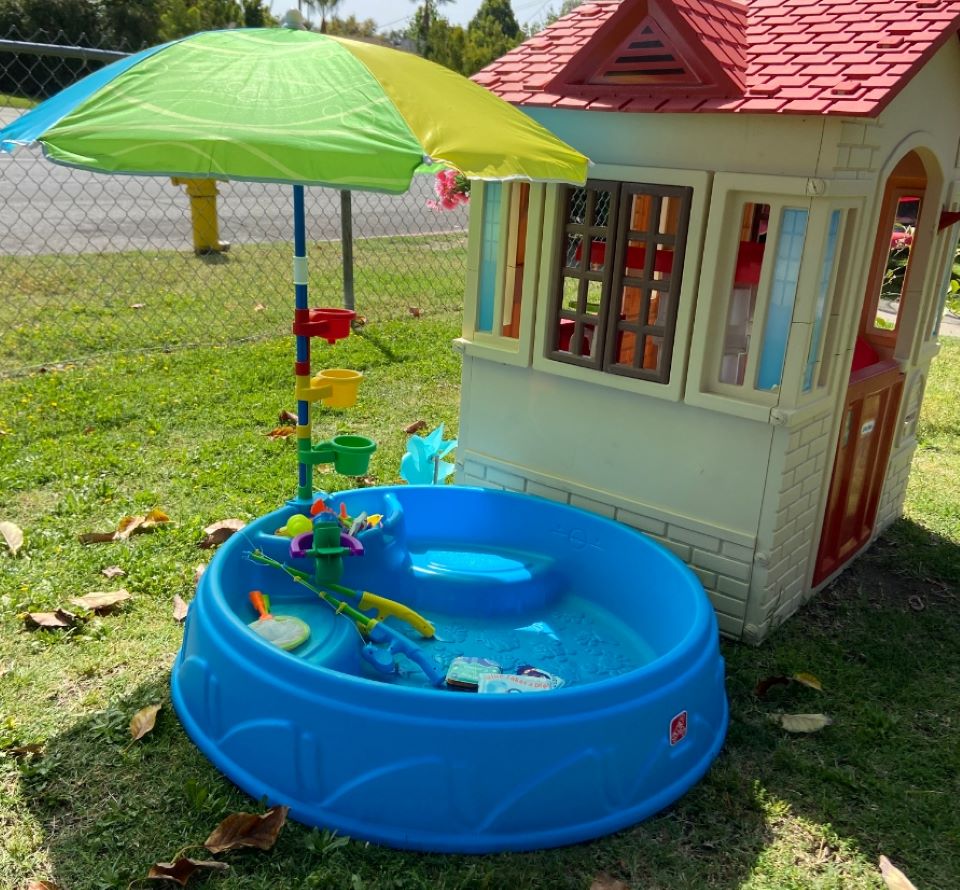 Pool with an umbrella next to a kids play house