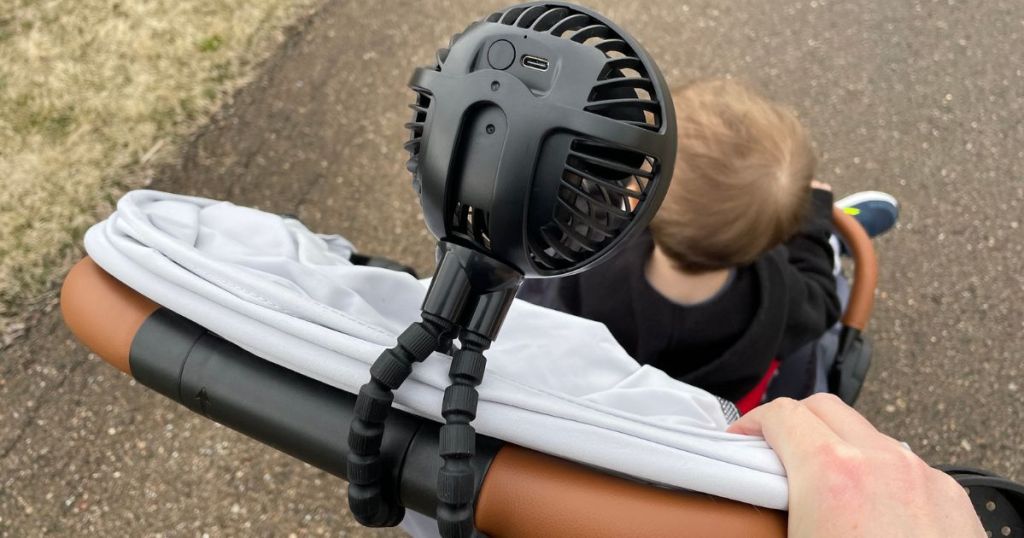 portable stroller fan attached to the push bar handle of a stroller with a little boy in it