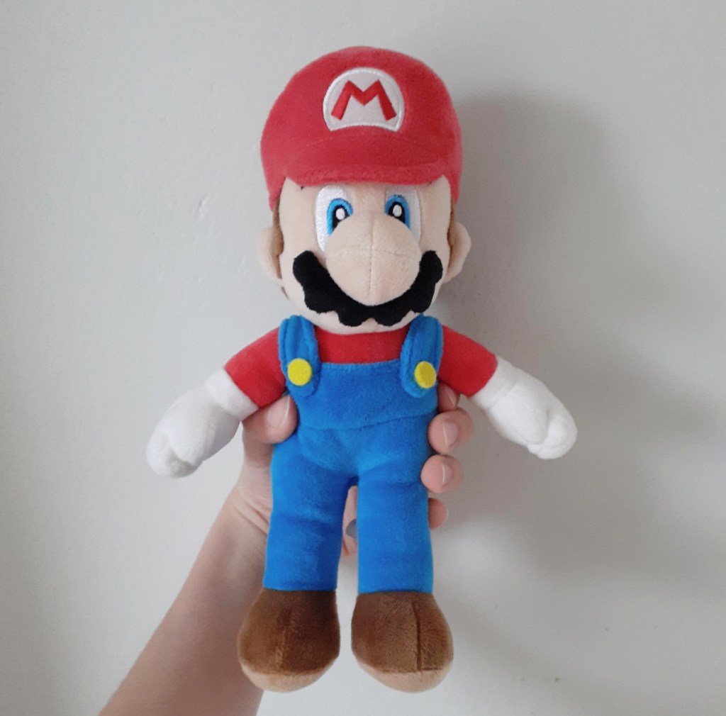 An Amazon product reviewer's hand holding a super mario plush toy