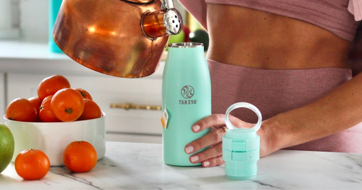 a woman pouring hot water into a Takeya Traveler Insulated Coffee Mug with leakproof lid in 25oz size