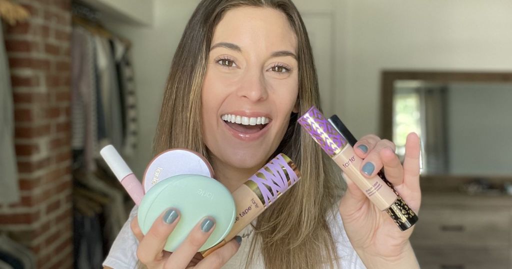 Woman holding several Tarte beauty products