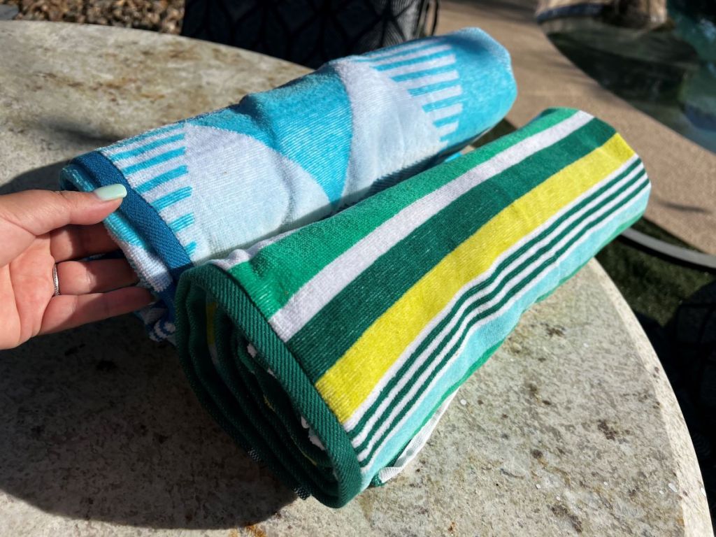 Hand holding The Big One Beach towel on a table