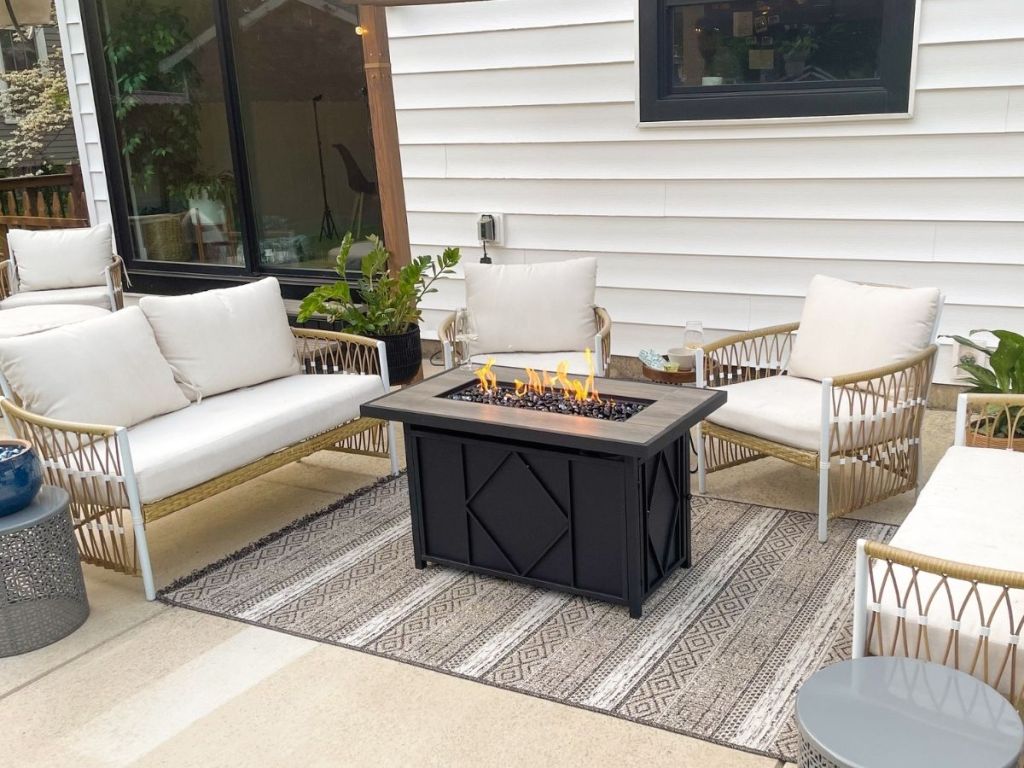 A patio set with a propane fire pit in the center from wayfair