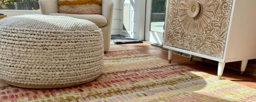 A Wayfair rug with a pouf ottoman and chair on it
