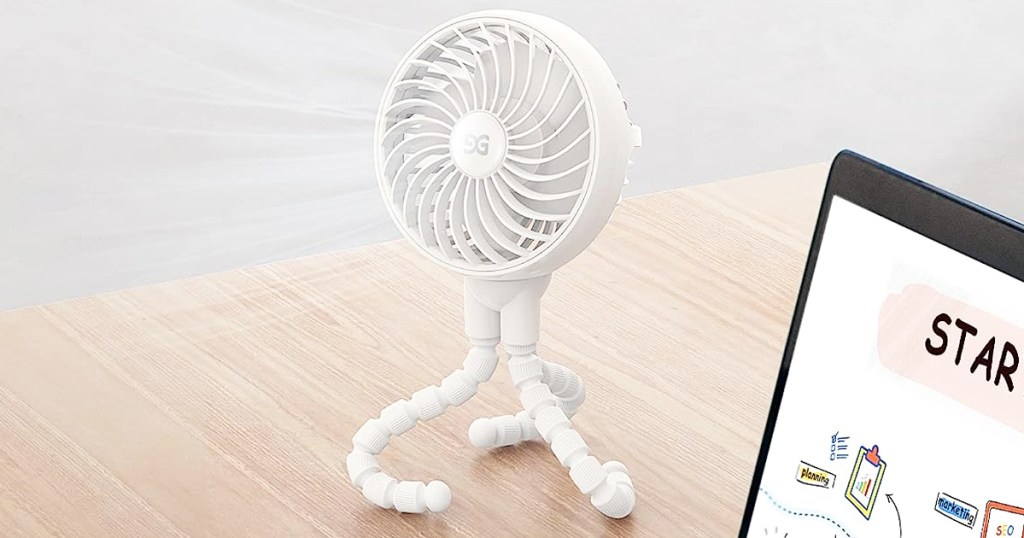 white fan with tripod legs on desk