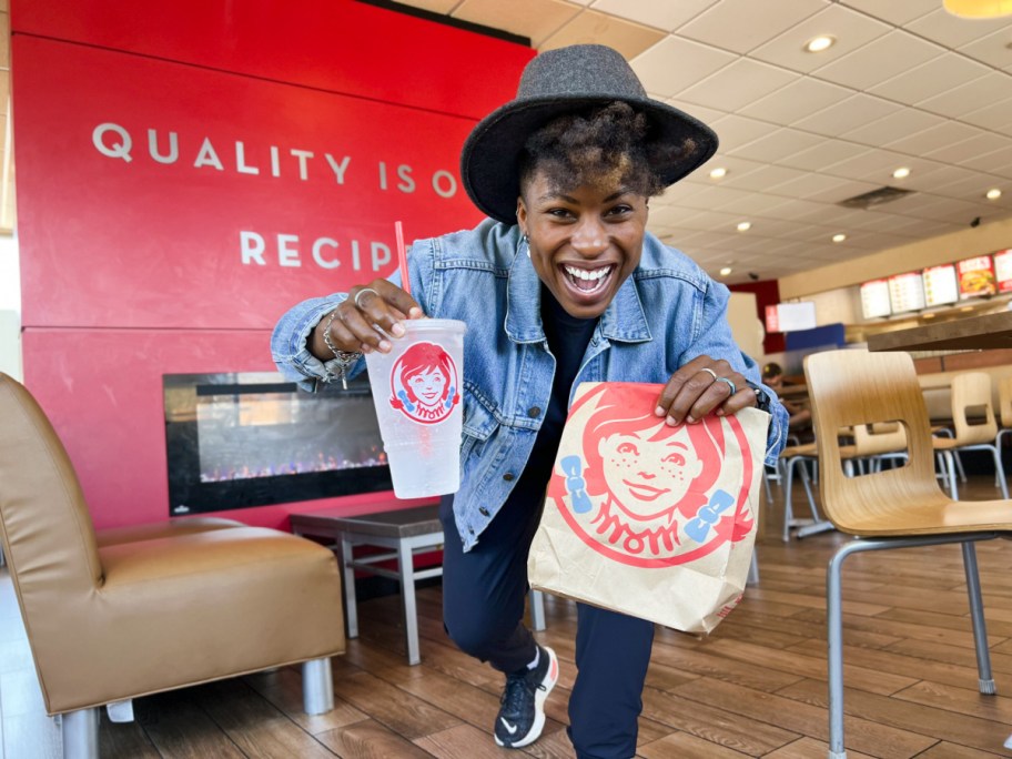 A woman in a Wendy's with a bag and a drink