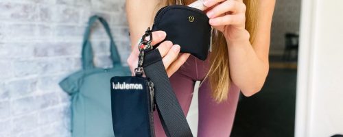 Woman putting lip gloss into Lululemon Wristlet in black
