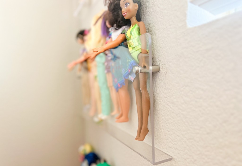 close up of acrylic wall shelf with colorful toy barbies and dolls