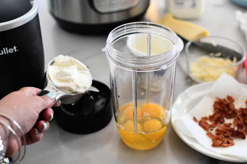 adding cream cheese to blender with eggs