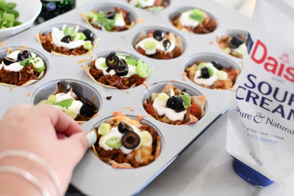 adding sour cream and toppings to taco cups