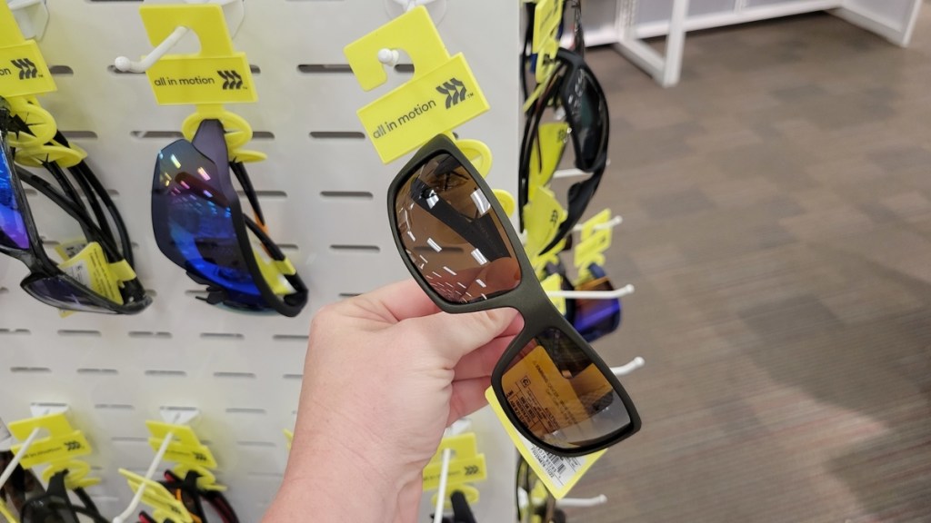 holding a pair of sunglasses with a yellow tag